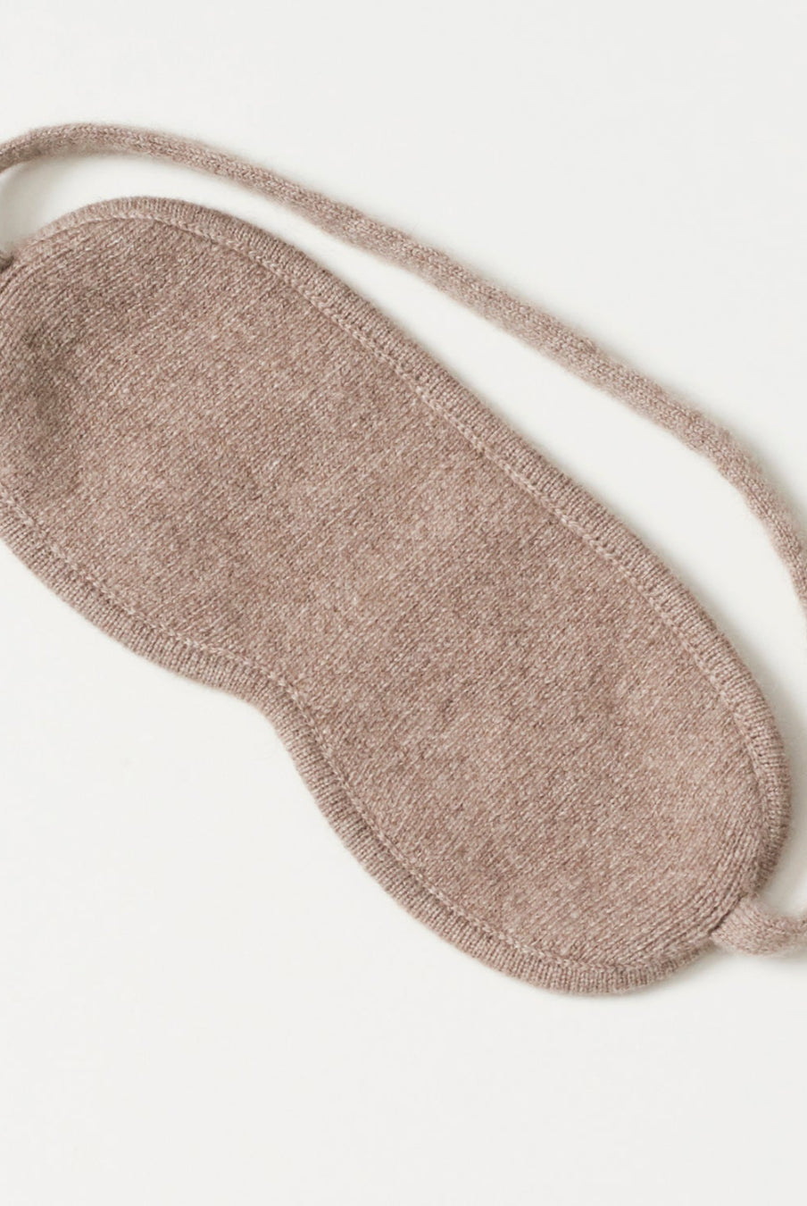 Cashmere sovemaske draperet elegant på en vandret flade.