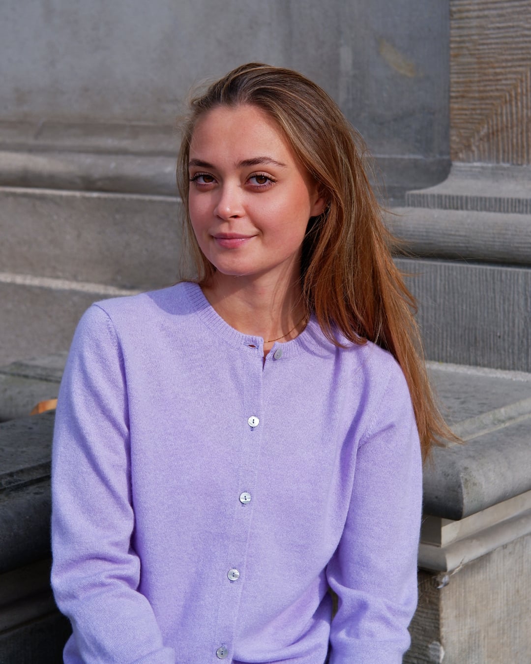 Kvinde iført Alma cardigan i Lavender, siddende.