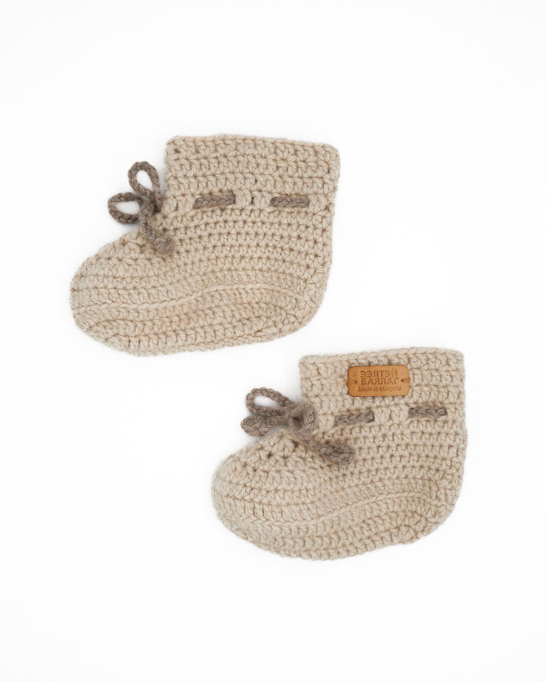 Saruul cashmere baby booties in Natural Sand on a white background.