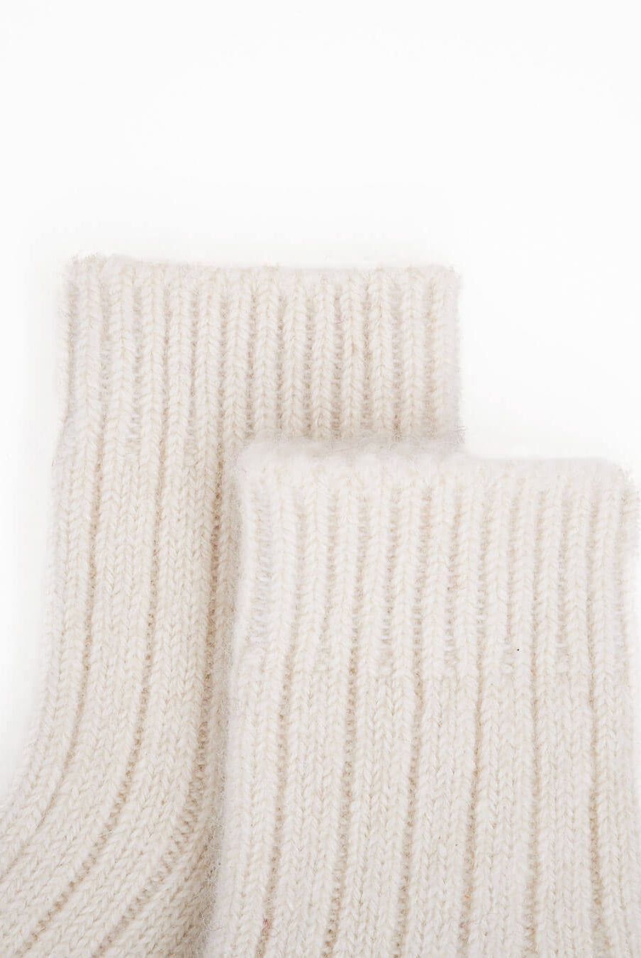 Detail of cashmere baby socks, 0–12 months, on a white background.
