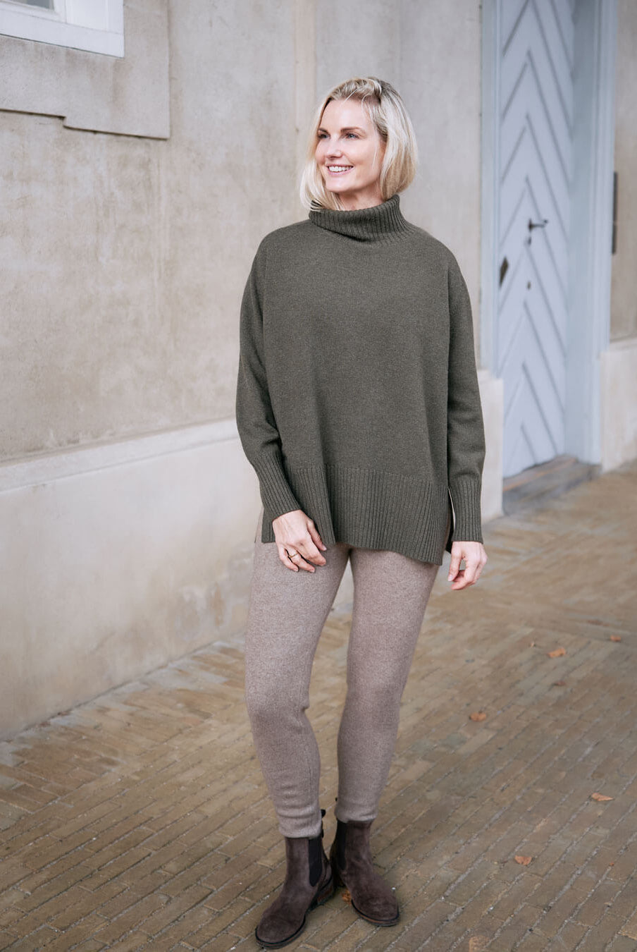 Model wearing cashmere leggings in natural taupe in front of door