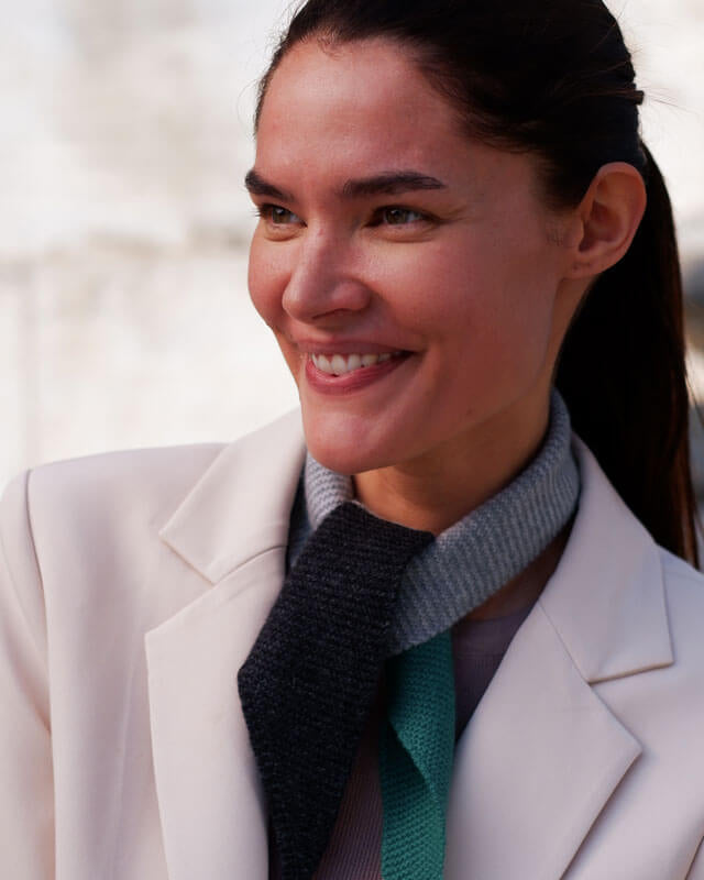 Elegant styling af cashmere Twilly-tørklædet, der smyger sig blødt om halsen i mørkegrå, lysegrå og grønne toner.