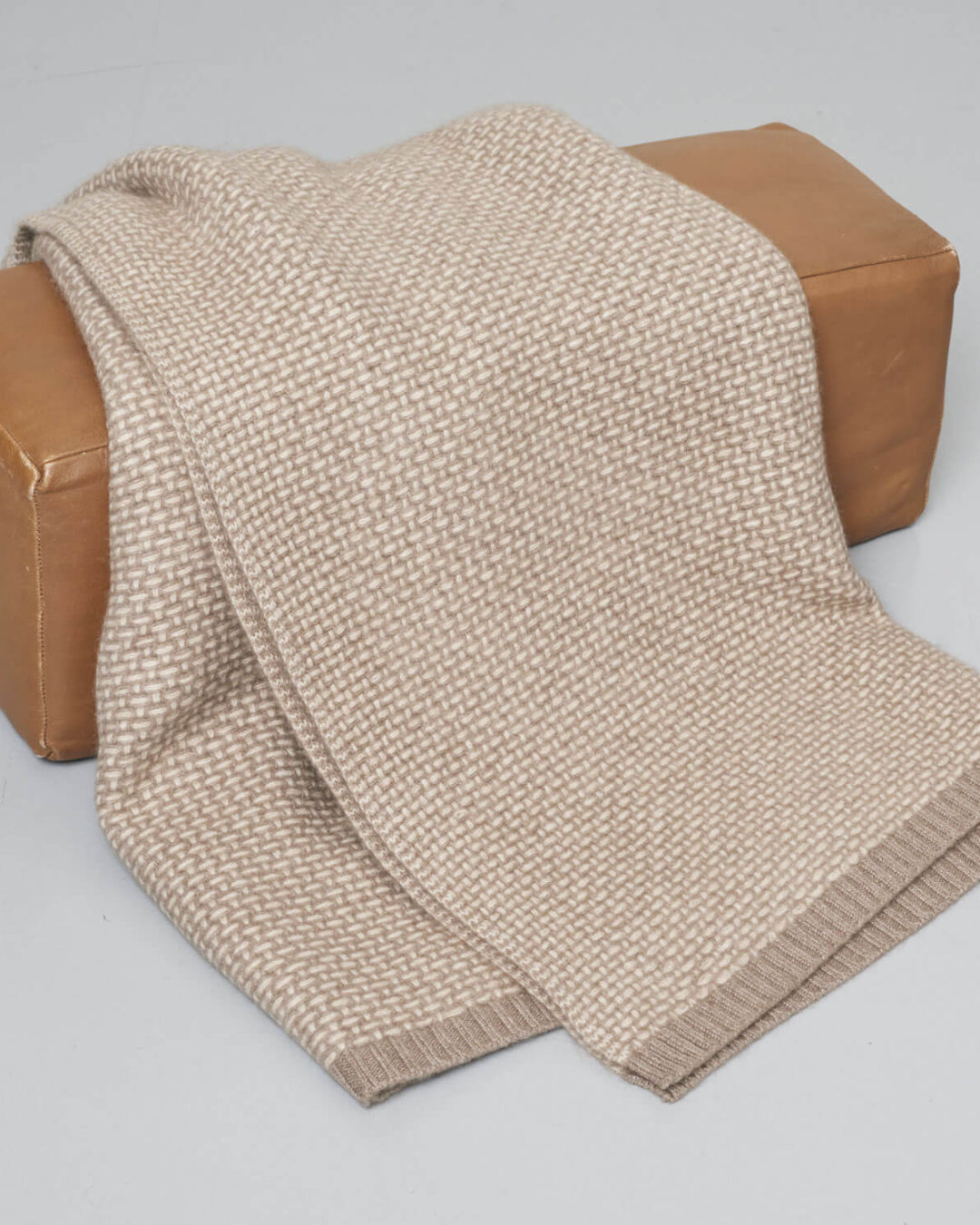En foldet cashmere plaid i naturlige beige nuancer.