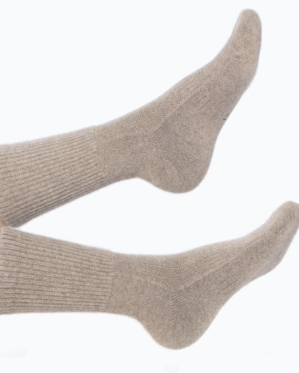Model iført mørk gråbeige cashmere sokker fra Undarmaa, afslappet i et hyggeligt miljø.