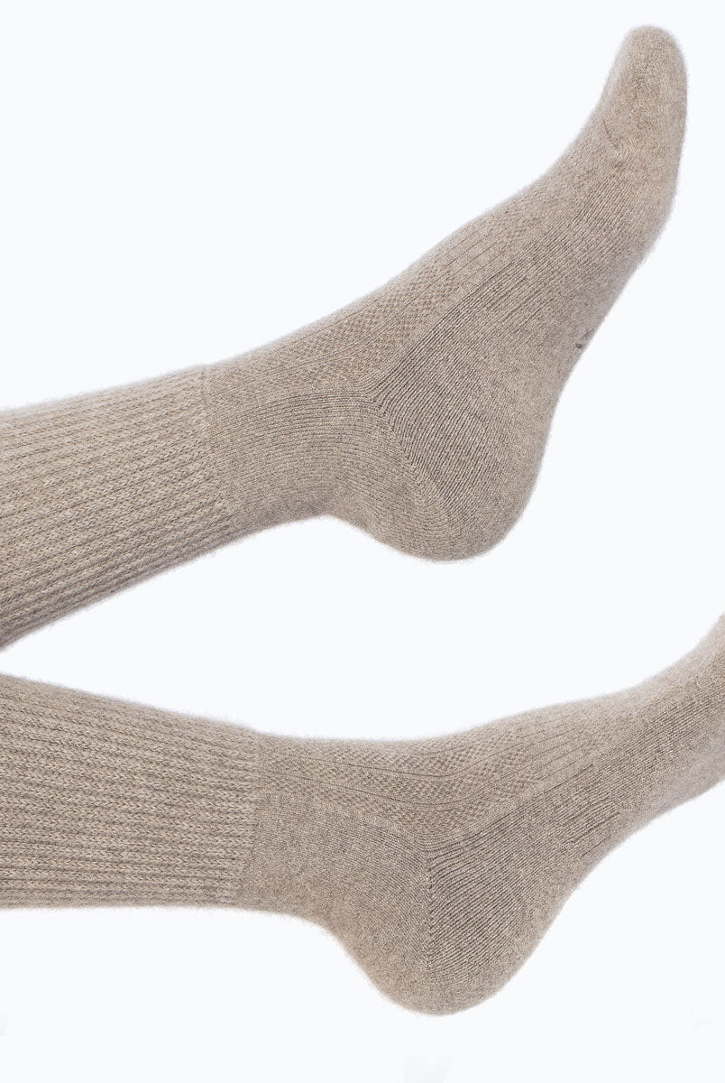 Model iført mørk gråbeige cashmere sokker fra Undarmaa, afslappet i et hyggeligt miljø.