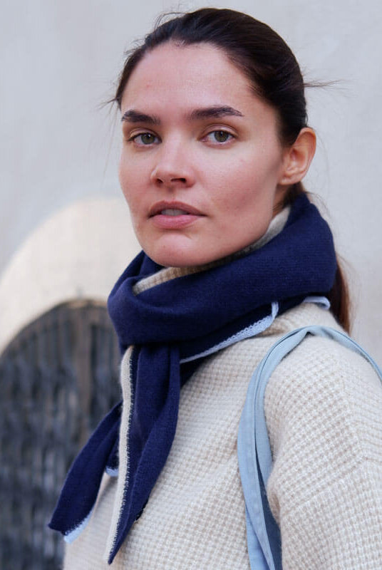 Modellen viser tørklædets elegante fald med kontrastkanter, perfekt til et klassisk look.