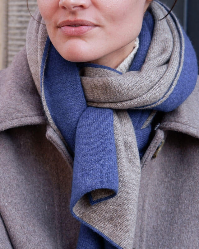 Nærbillede af det bløde cashmere halstørklæde, der fremhæver de fine vævninger i klassisk blå og taupe.