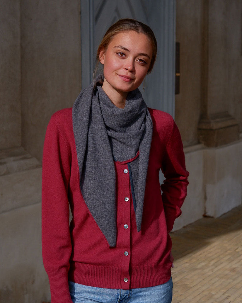 Modellen bærer det mørkegrå tørklæde med stil, og de kontrasterende kanter tilføjer et elegant farvespil.