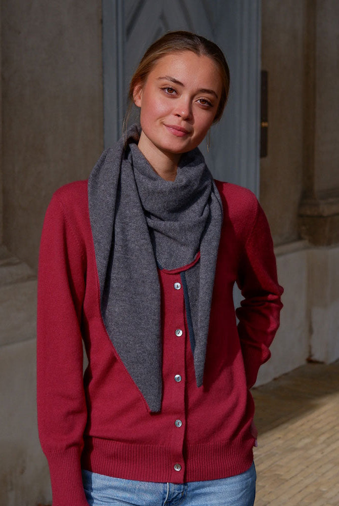 Modellen bærer det mørkegrå tørklæde med stil, og de kontrasterende kanter tilføjer et elegant farvespil.