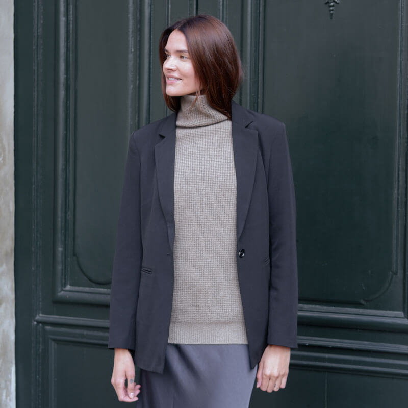 model iført rullekrave i en earth taupe farve kombineret med en sort blazer