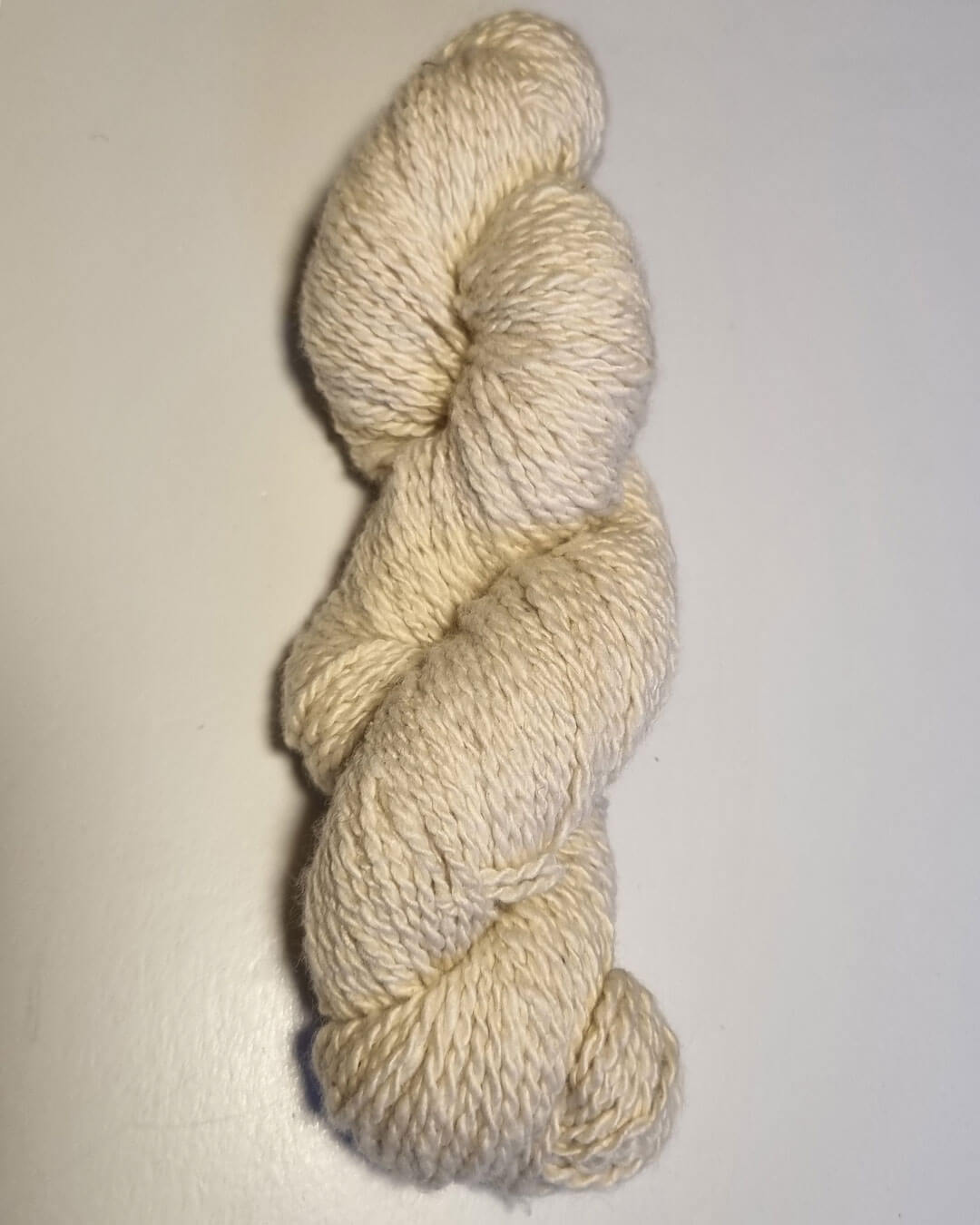 Håndspundet cashmeregarn i natural white på bord.