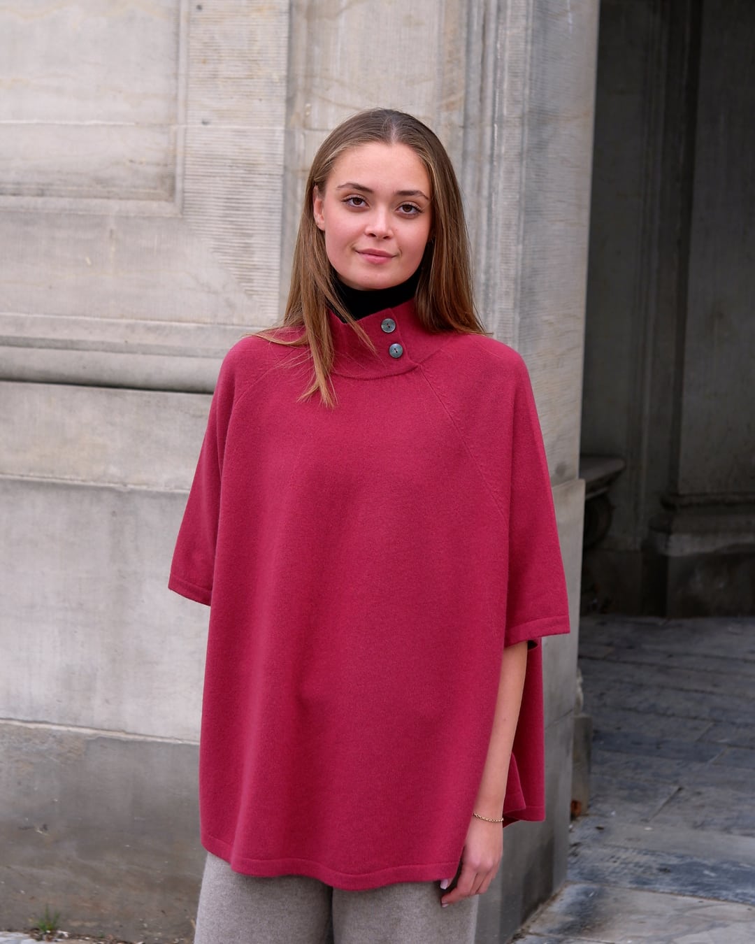 Kvinde iført cashmere poncho Enkh i Raspberry med høj hals og knapper.