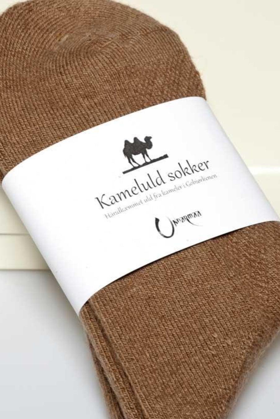 Detaljebillede af kameluldsokker med label, der viser materialet og kvaliteten.