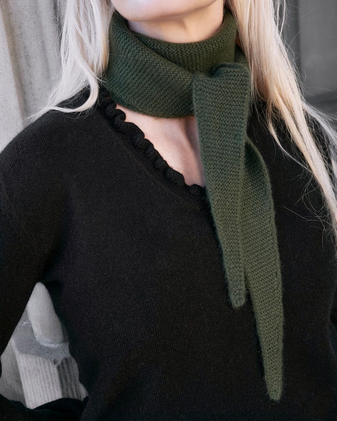 Nærbillede af flæsedetaljer ved halsudskæring, Oyu cashmere bluse i Black.