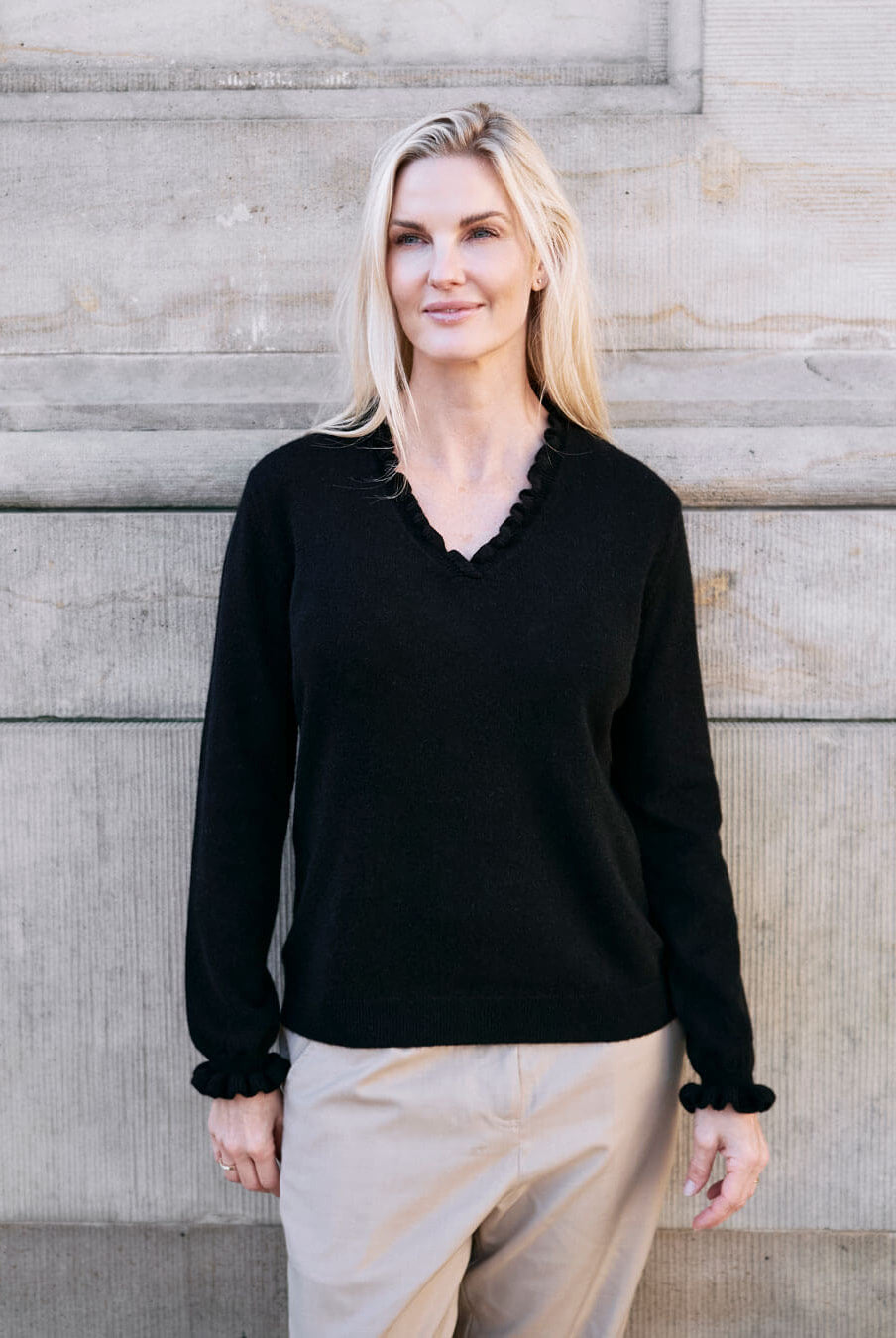 Kvinde iført cashmere bluse i Black med flæsedetaljer ved halsudskæring.
