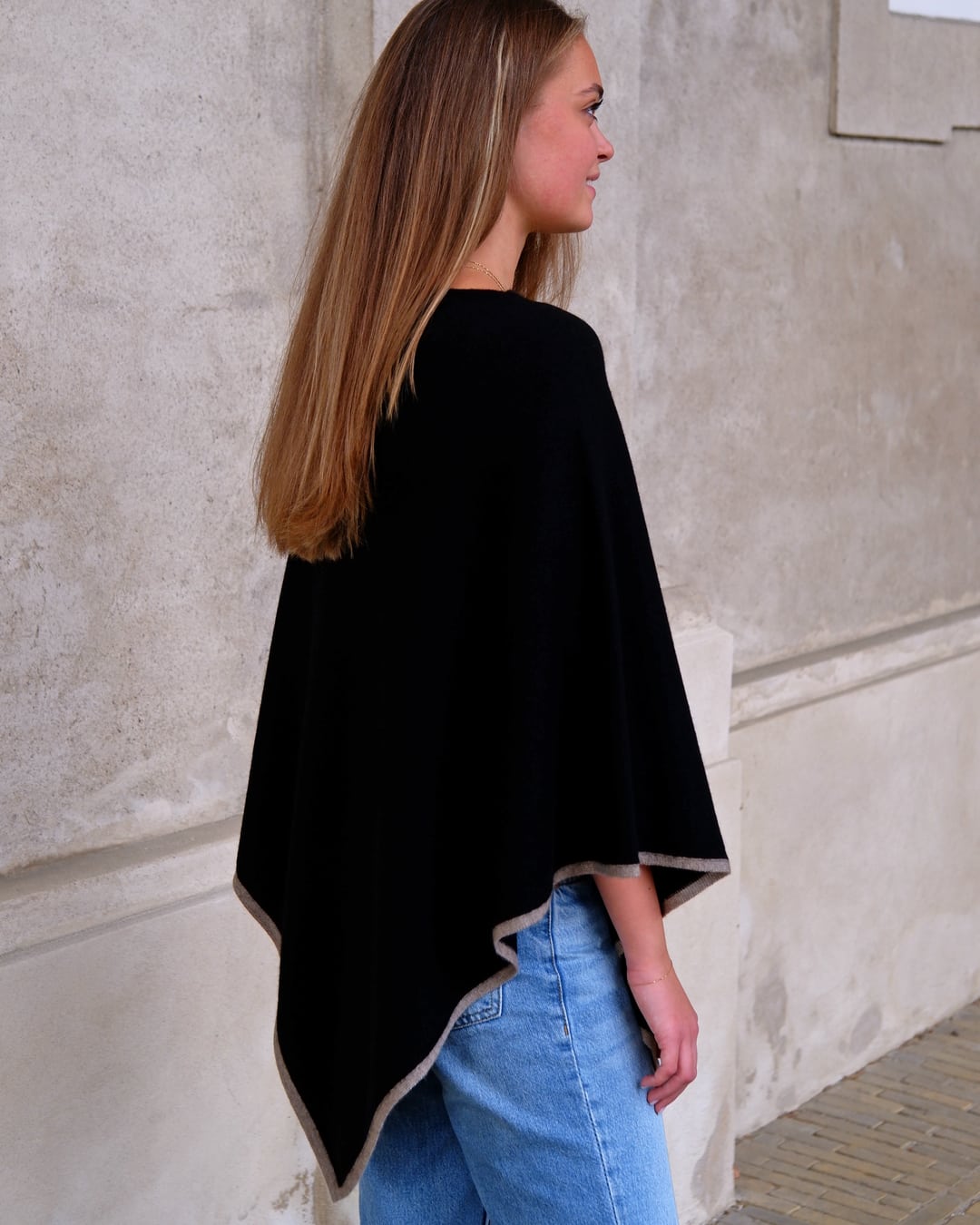 Sort cashmere poncho Sarnai set bagfra, med taupefarvet kontrastkant.