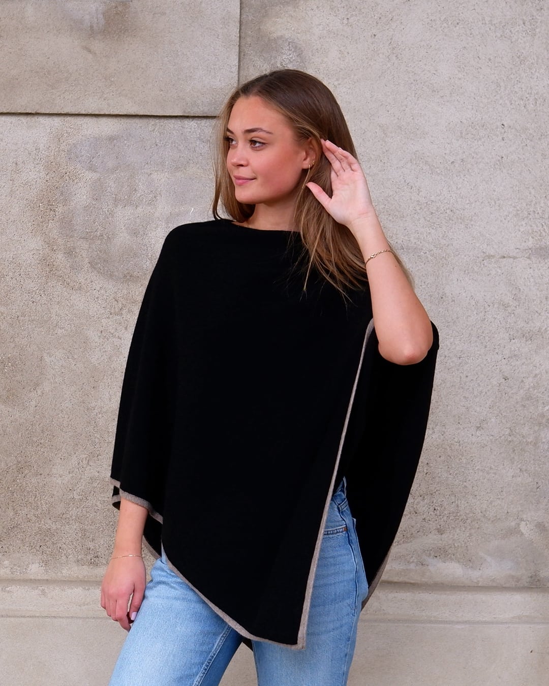Kvinde iført sort cashmere poncho Sarnai med taupefarvet kontrastkant.