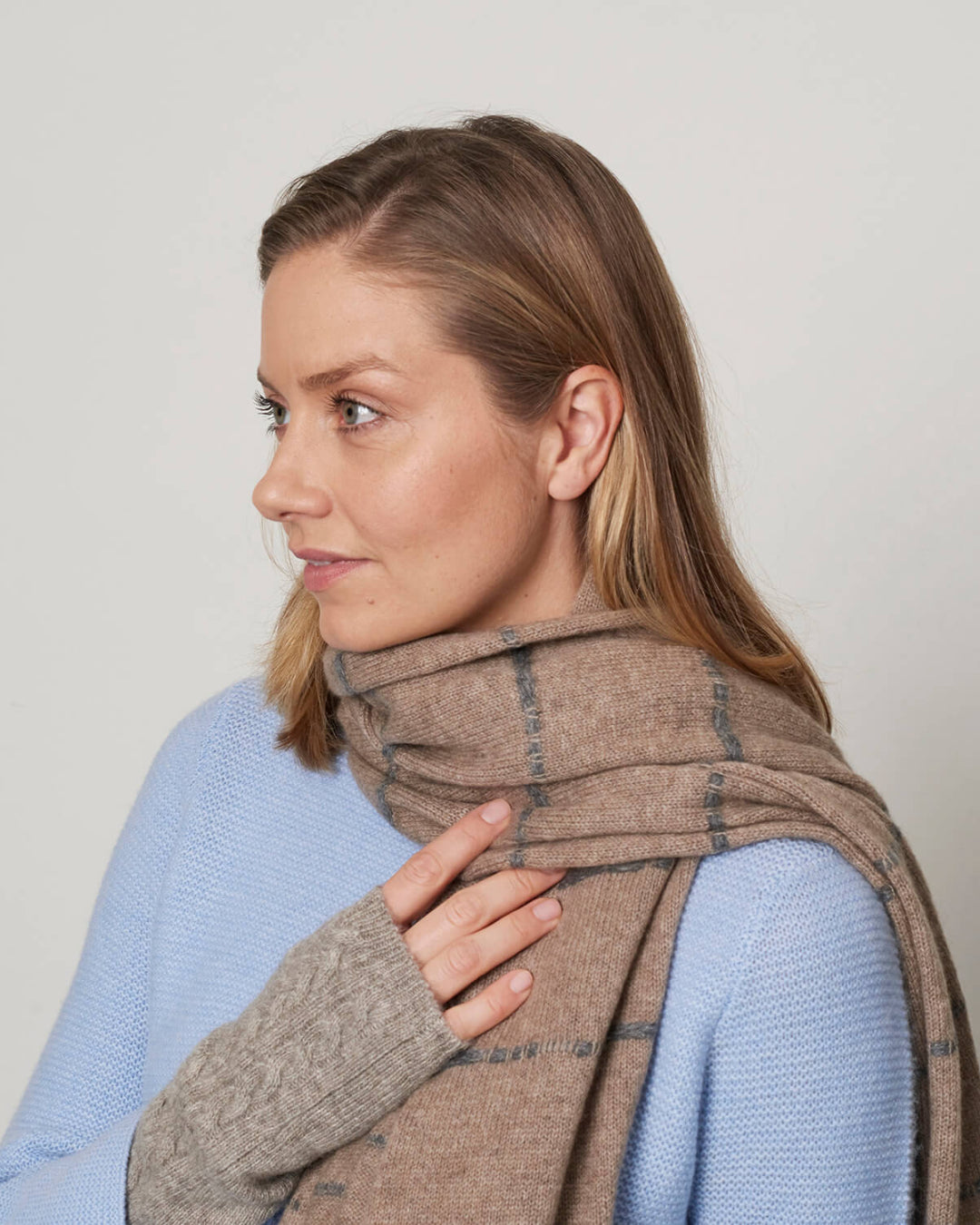 Model iført det stribede cashmere tørklæde i mørk gråbeige naturfarve og grå striber.