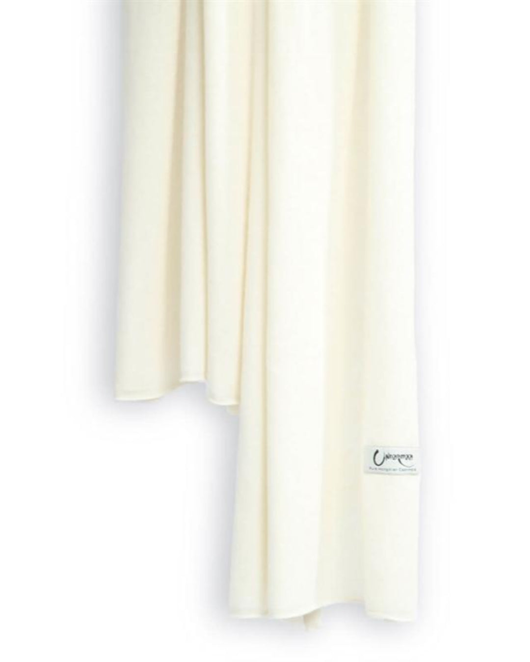 Det store cashmere tørklæde, her i naturfarvet hvid hænger løst ned.
