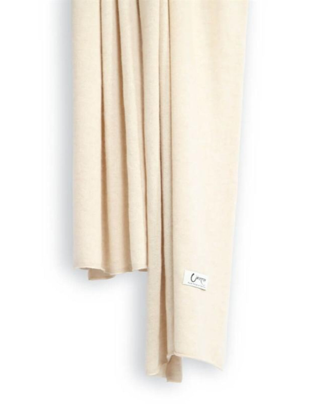 Det store cashmere tørklæde, her i naturfarvet lys beige hænger løst ned.
