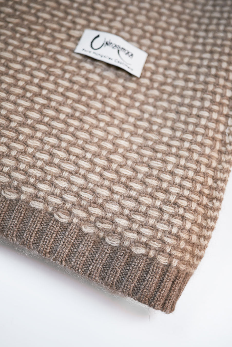 Kantdetalje på Taiga cashmere plaid med ribstrikket afslutning og Undarmaa-label.