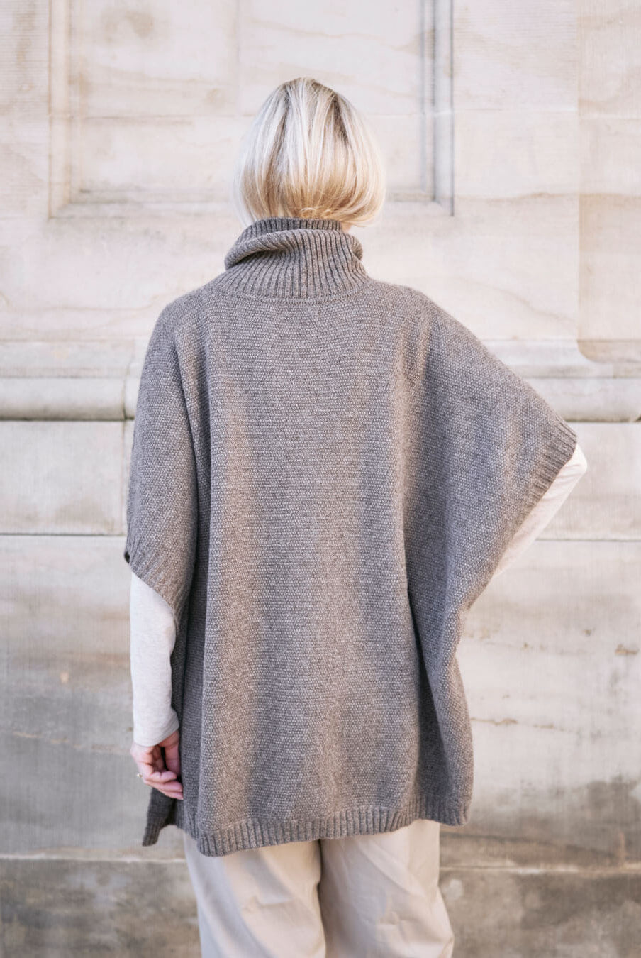 Model bære Tara yakuld poncho med rullekrave i Yak Dark Grey set bagfra.