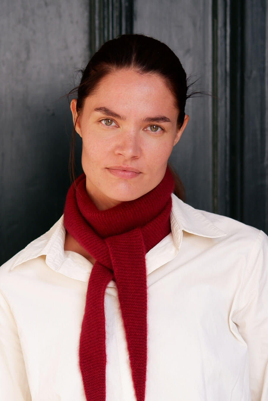 Model med Taiga cashmere trekanttørklæde i Bordeaux over lys skjorte.
