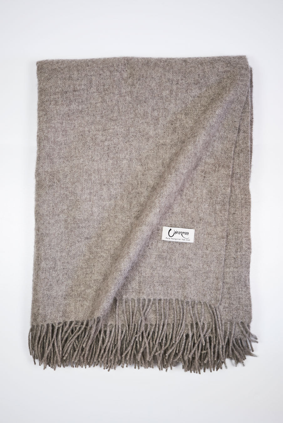 Vævet plaid i 100% yakuld, platinum grey, med frynser og Undarmaa-label.