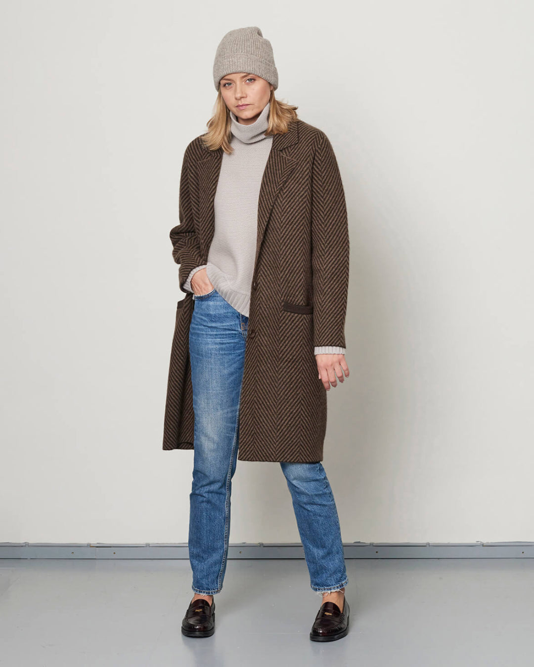 Model iført yakuld frakke i et klassisk sildebensmønster, kombineret med lys mocha og chocolate farver.