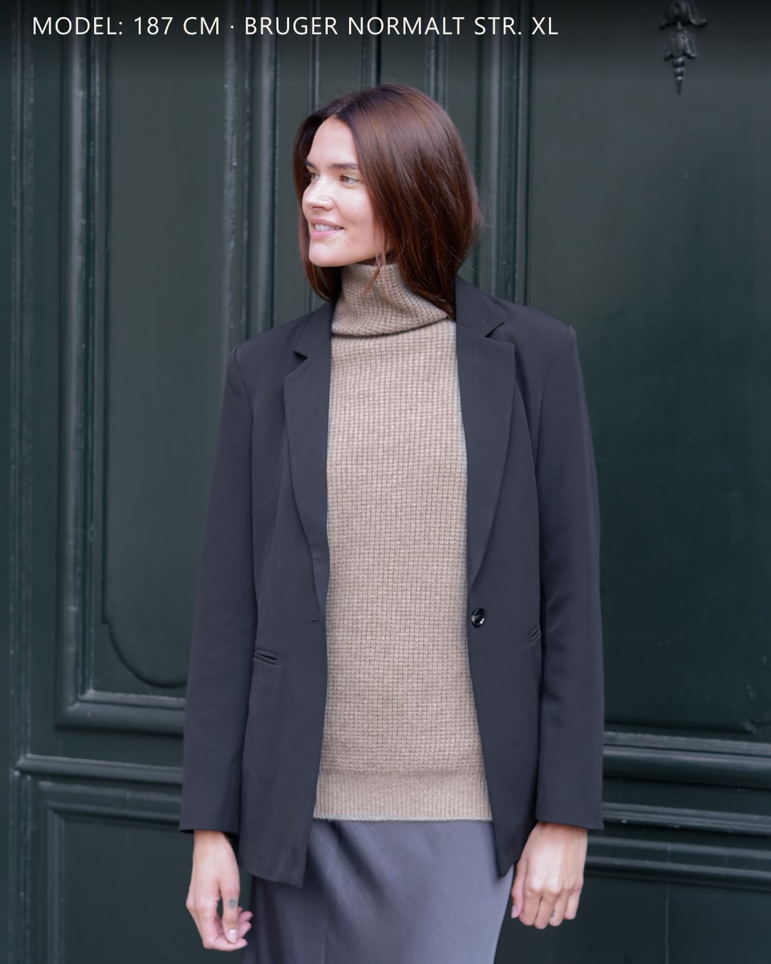 Kvinde iført Zaya turtleneck i Natural taupe cashmere under blazer, udendørs.