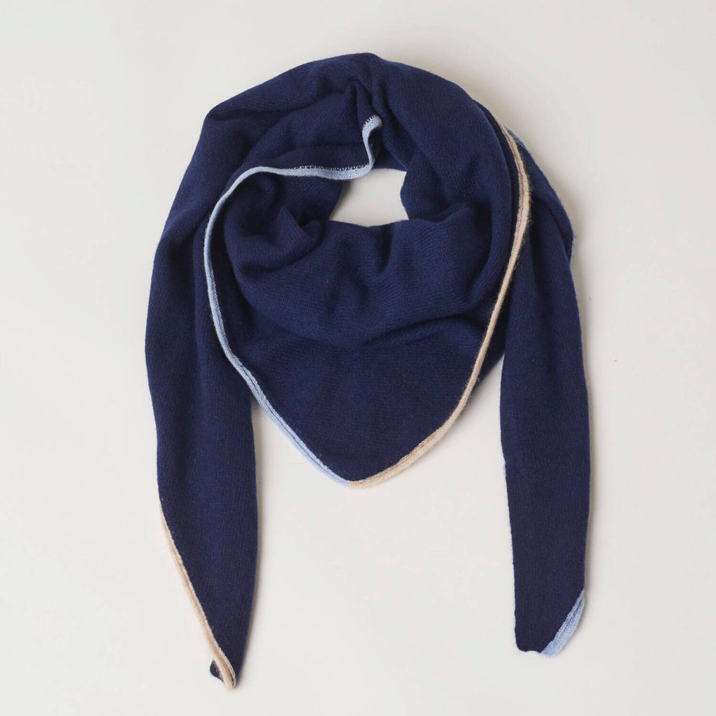 Trekantet cashmere tørklæde i marineblå med kontrastkant, draperet elegant.