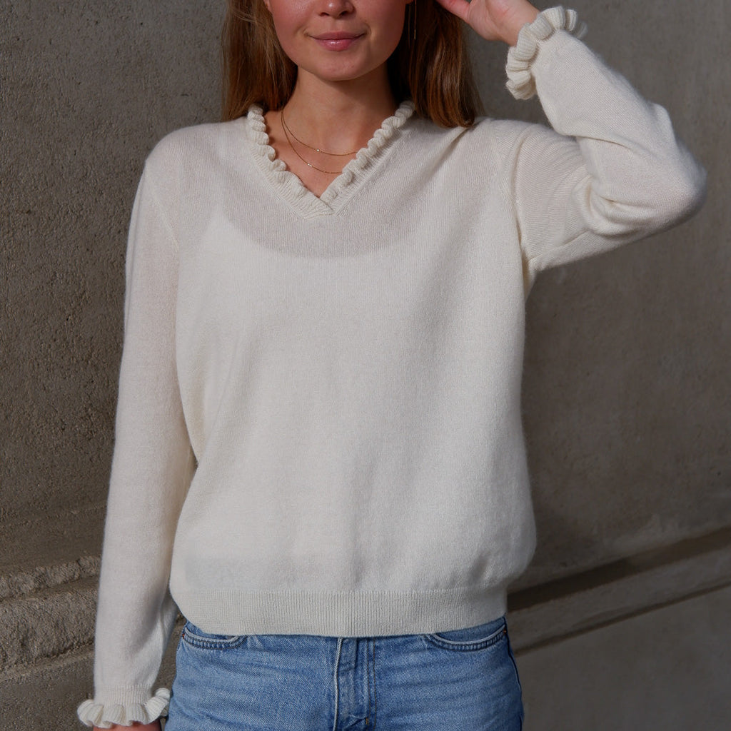 Kvinde iført cashmere bluse i med flæsedetaljer ved halsudskæring, Natural White.