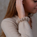 Model iført cashmere bluse i Natural Sand med flæsedetaljer ved halsudskæring.