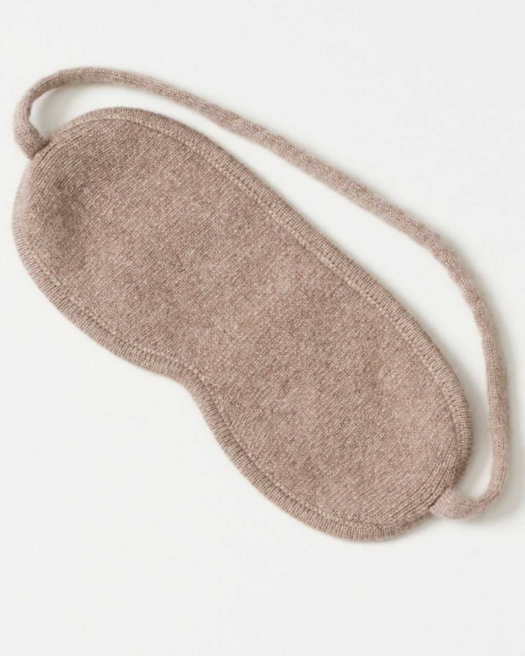 Cashmere sovemaske draperet elegant på en vandret flade.