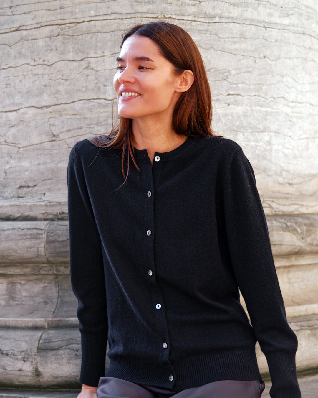 Kvinde iført Alma cardigan i Black, smilende.