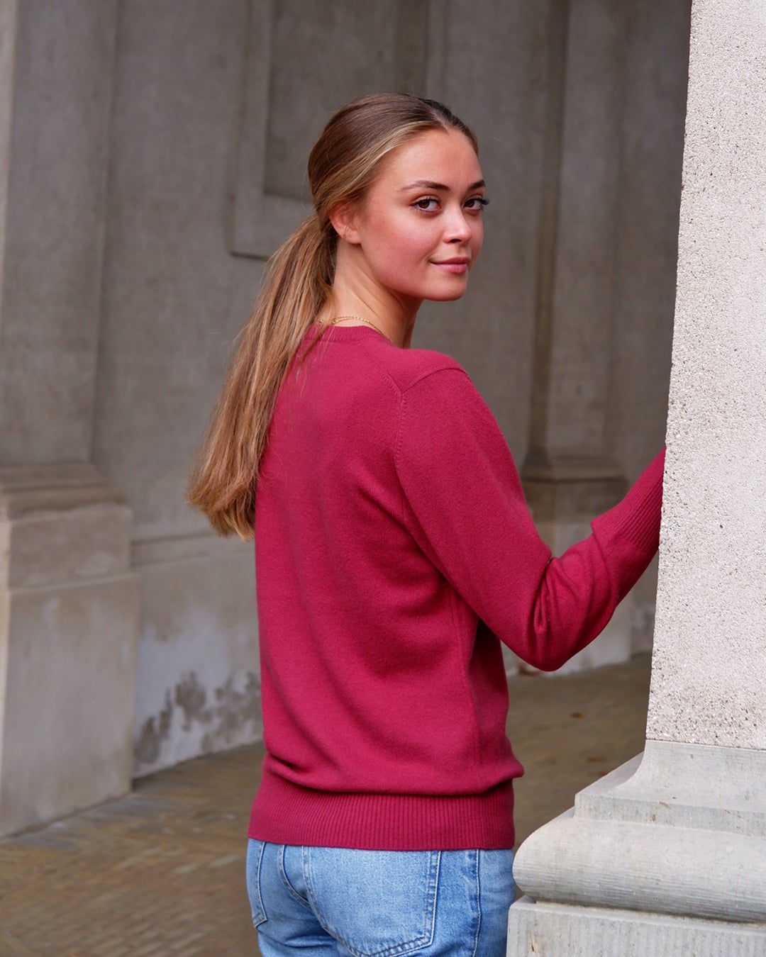 Kvinde iført Alma cardigan i Raspberry, set bagfra.