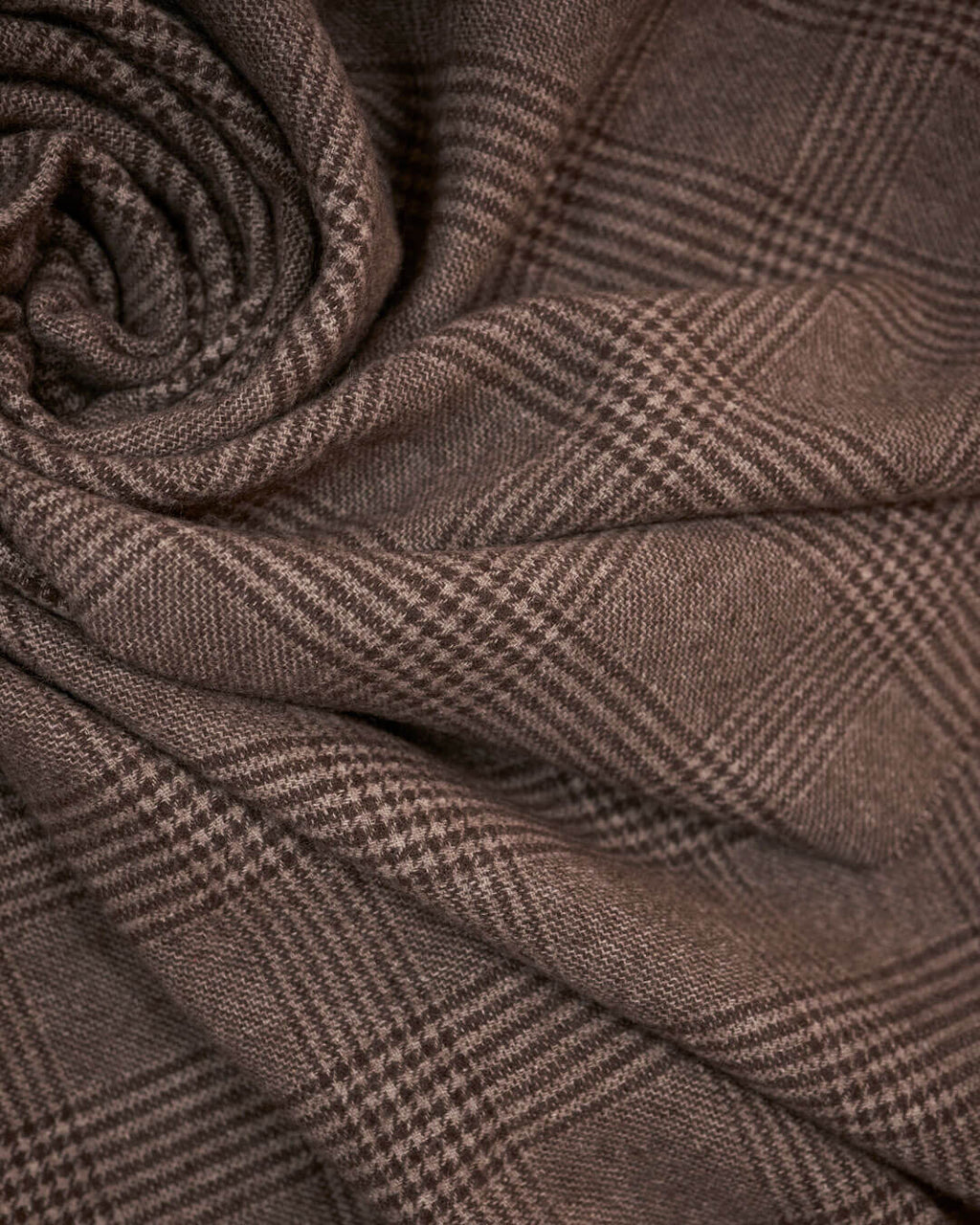 Detaljebillede af yakuld plaid i brunternet mønster, vist foldet i bløde lag