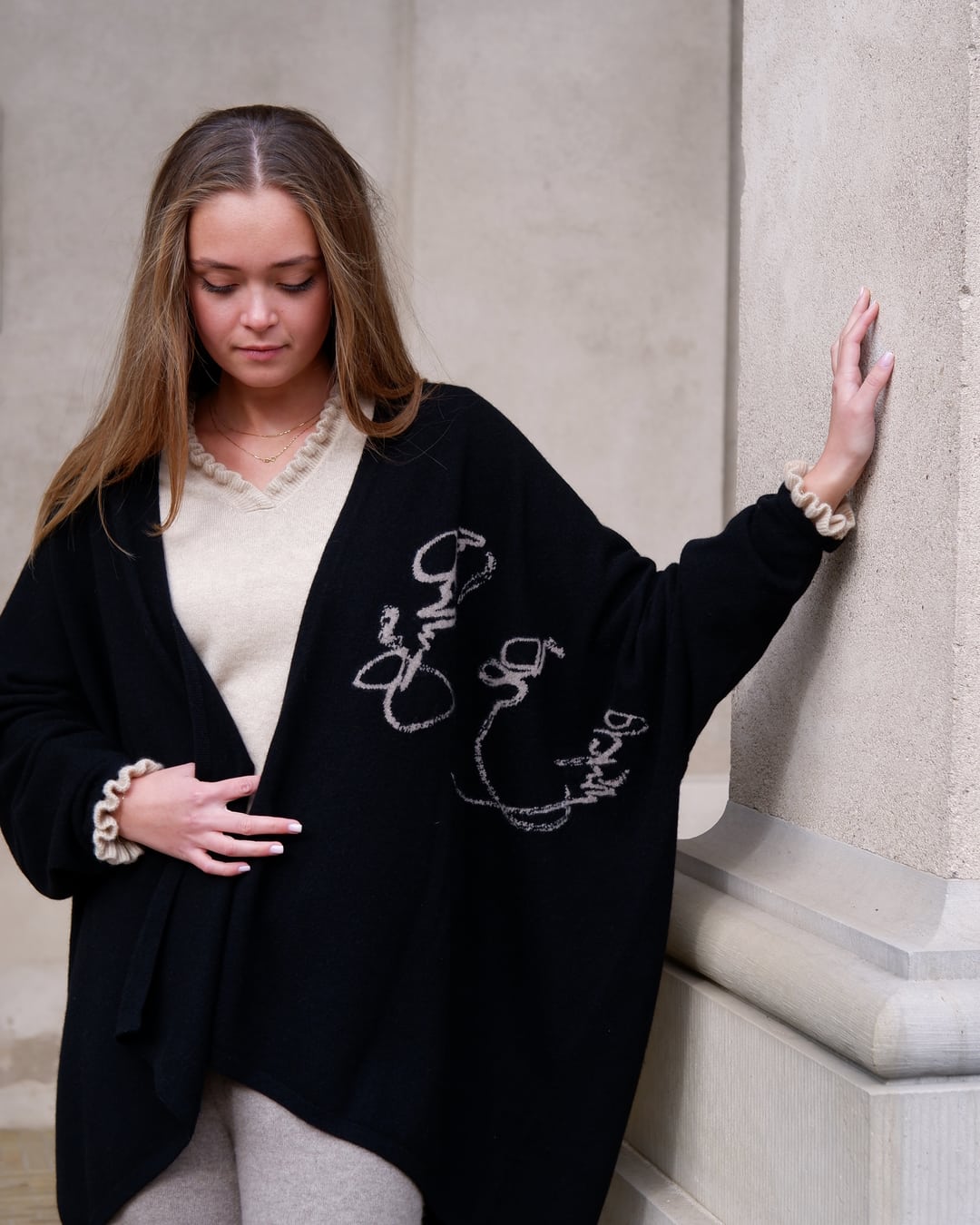Cashmere-kappe Anu i sort med indstrikkede mongolske skrifttegn ("Vores arv") langs kanten.