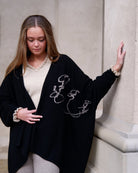 Cashmere-kappe Anu i sort med indstrikkede mongolske skrifttegn ("Vores arv") langs kanten.
