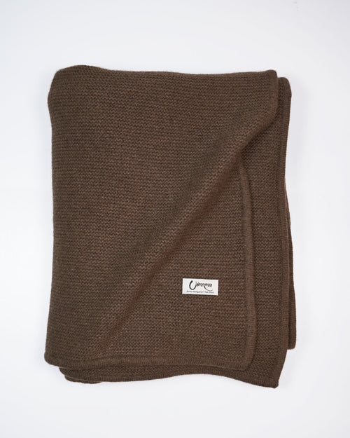 Strikket Barkhan plaid i yakuld, set ovenfra i varm brun nuance.