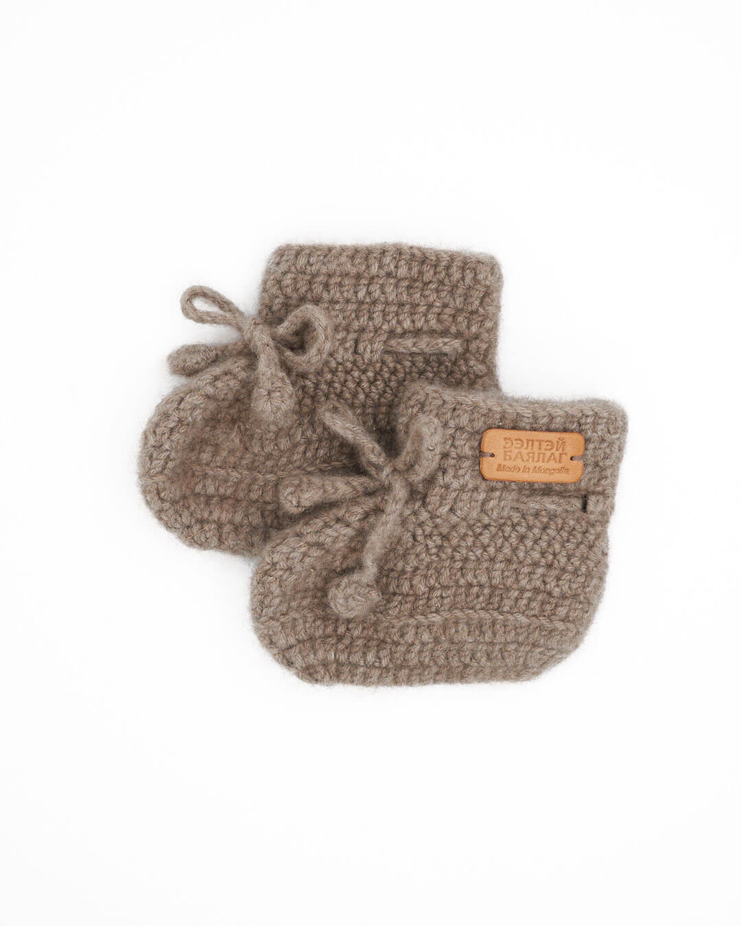 Saruul cashmere baby booties in Natural taupe on a white background.