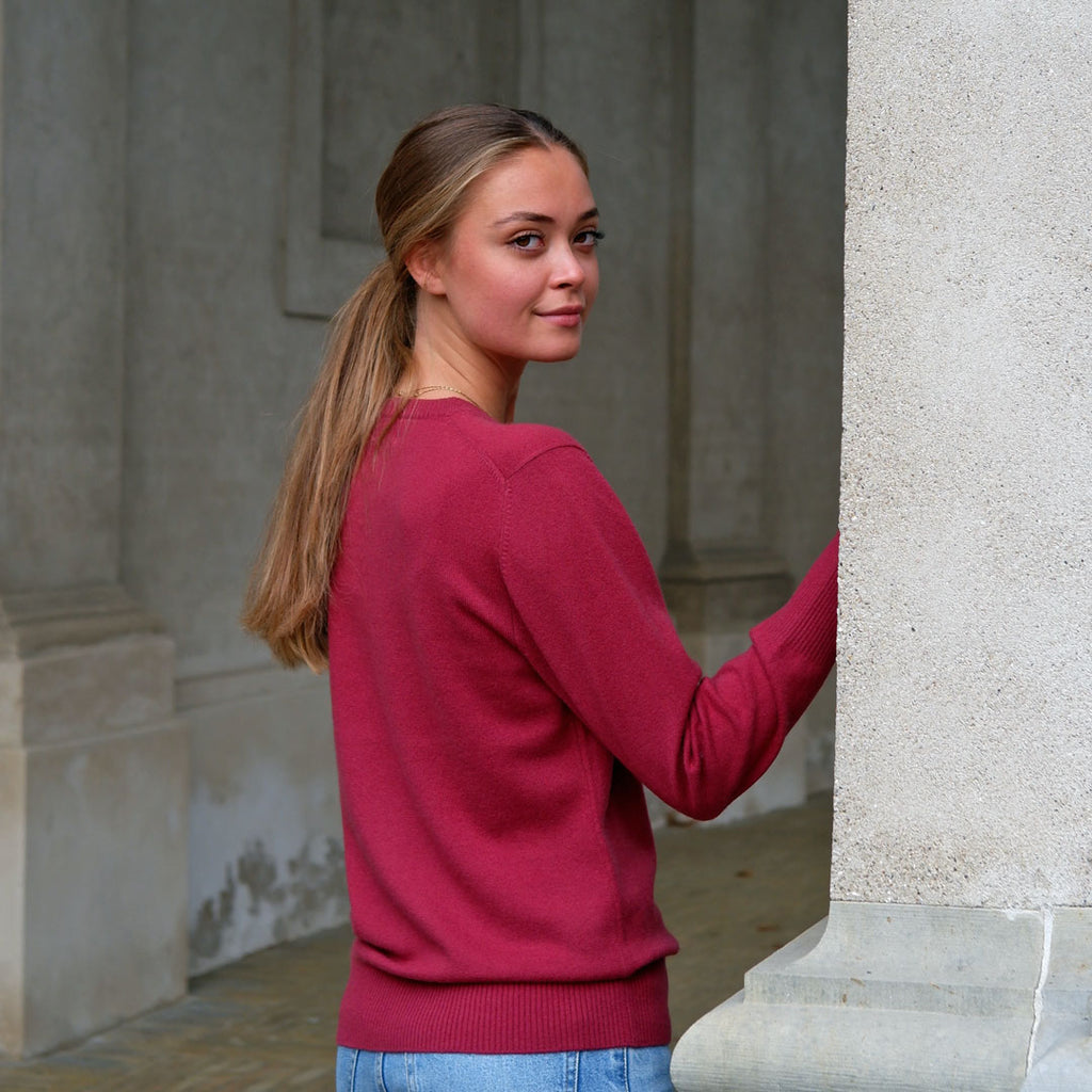 Kvinde set bagfra iført en Pinot Red cashmere cardigan, kigger over skulderen.