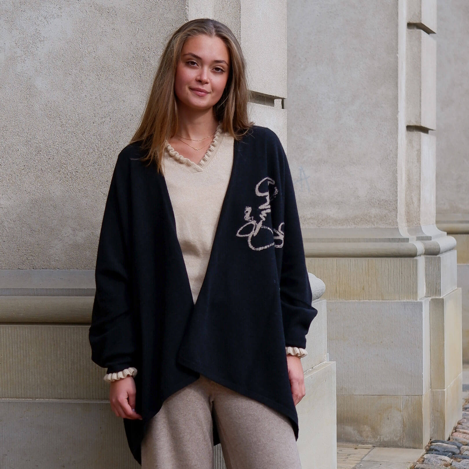 Helbillede af model iført den sorte cashmere kappe, der viser dens fulde længde og unikke design med det mongolske skrifttegn.