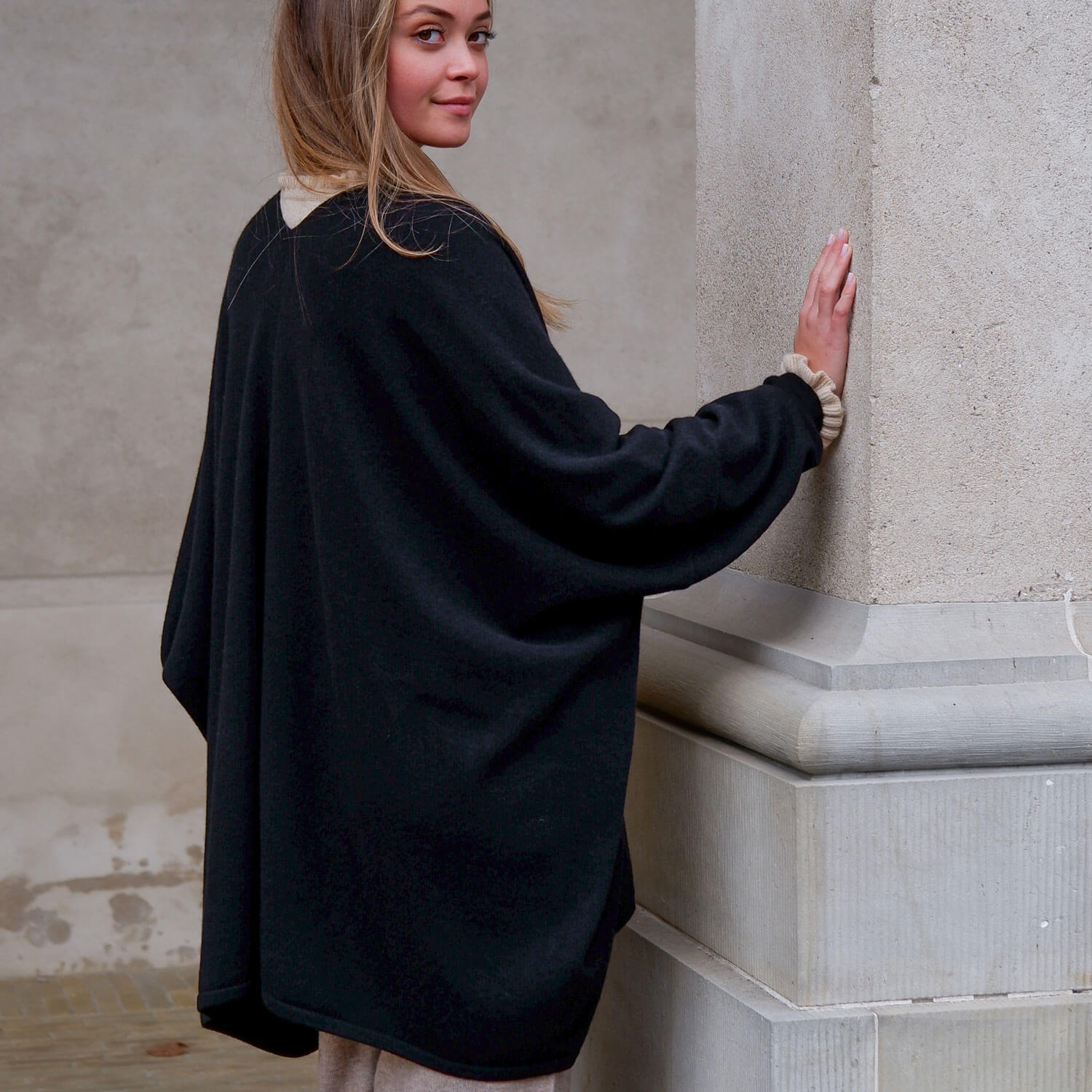 Helbillede af model iført den sorte cashmere kappe set bagfra.
