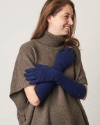 Model præsenterer lange cashmere handsker i en marineblå farve.