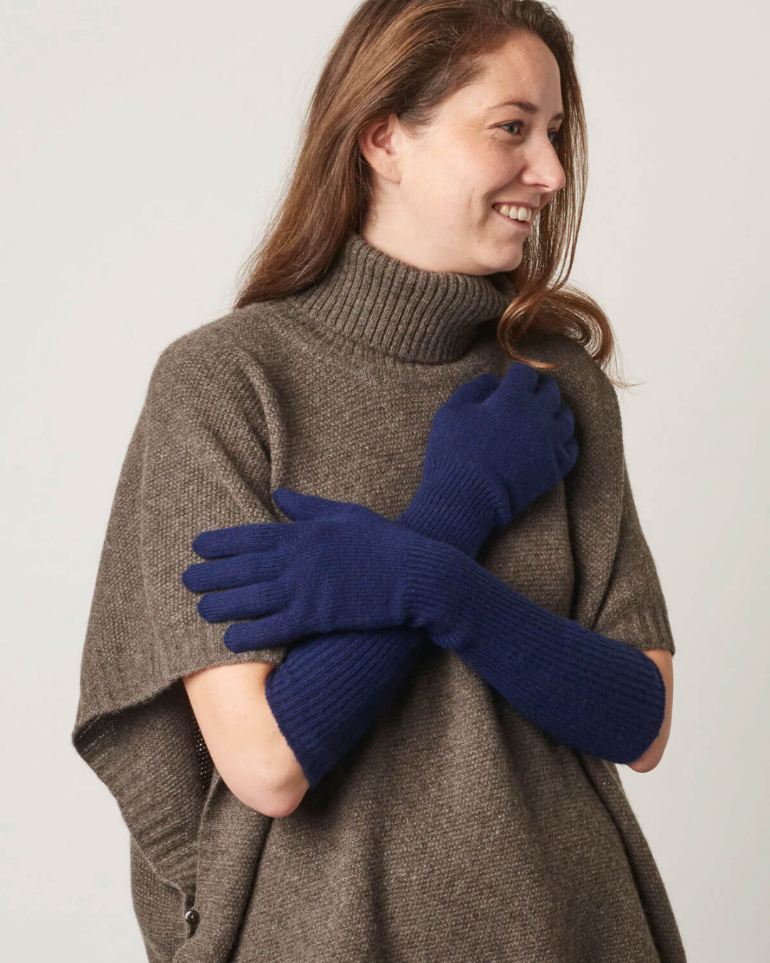 Model præsenterer lange cashmere handsker i en marineblå farve.