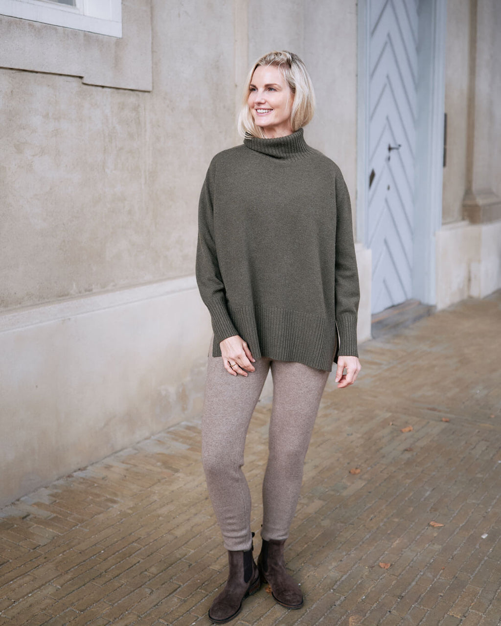 Model iført cashmere leggings i natural taupe foran dør