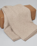 En foldet cashmere plaid i naturlige beige nuancer.