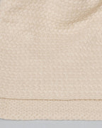 Detalje af den fine tekstur på cashmere plaiden i en elegant lys beige farve.