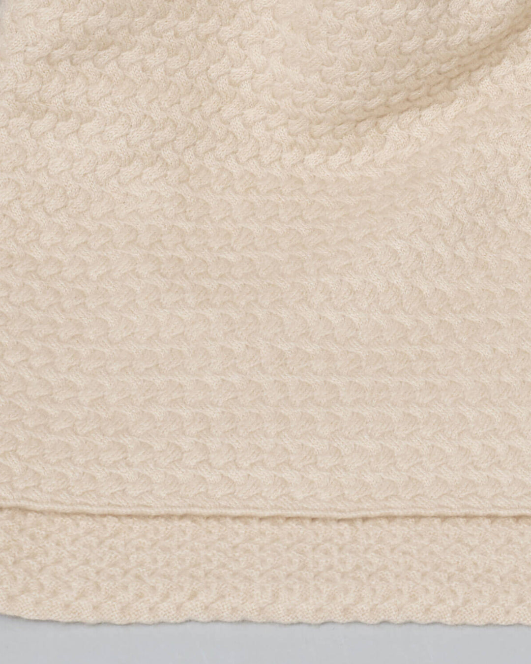 Detalje af den fine tekstur på cashmere plaiden i en elegant lys beige farve.